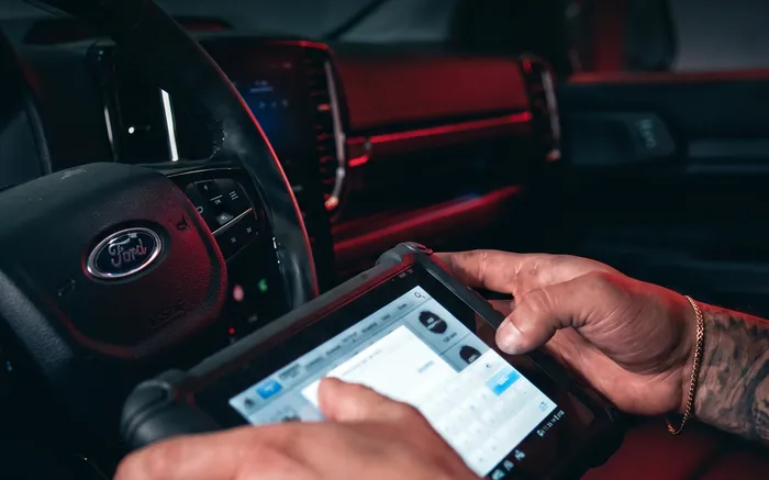Técnico da TS Auto Center com o scanner de diagnóstico conectado e a tela acesa, dentro da caminhonete