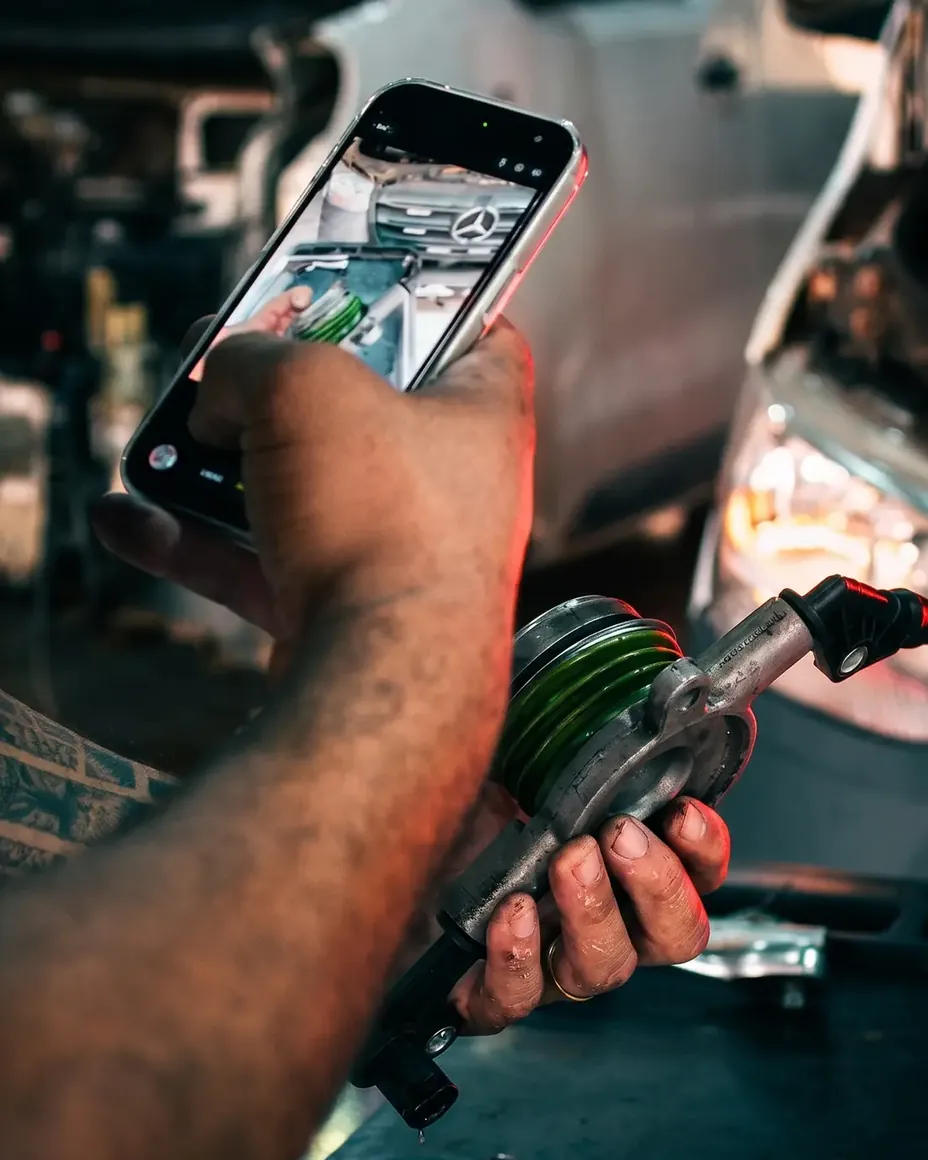 Mecânico da TS Auto Center fotografando a peça trocada para enviar no WhatsApp