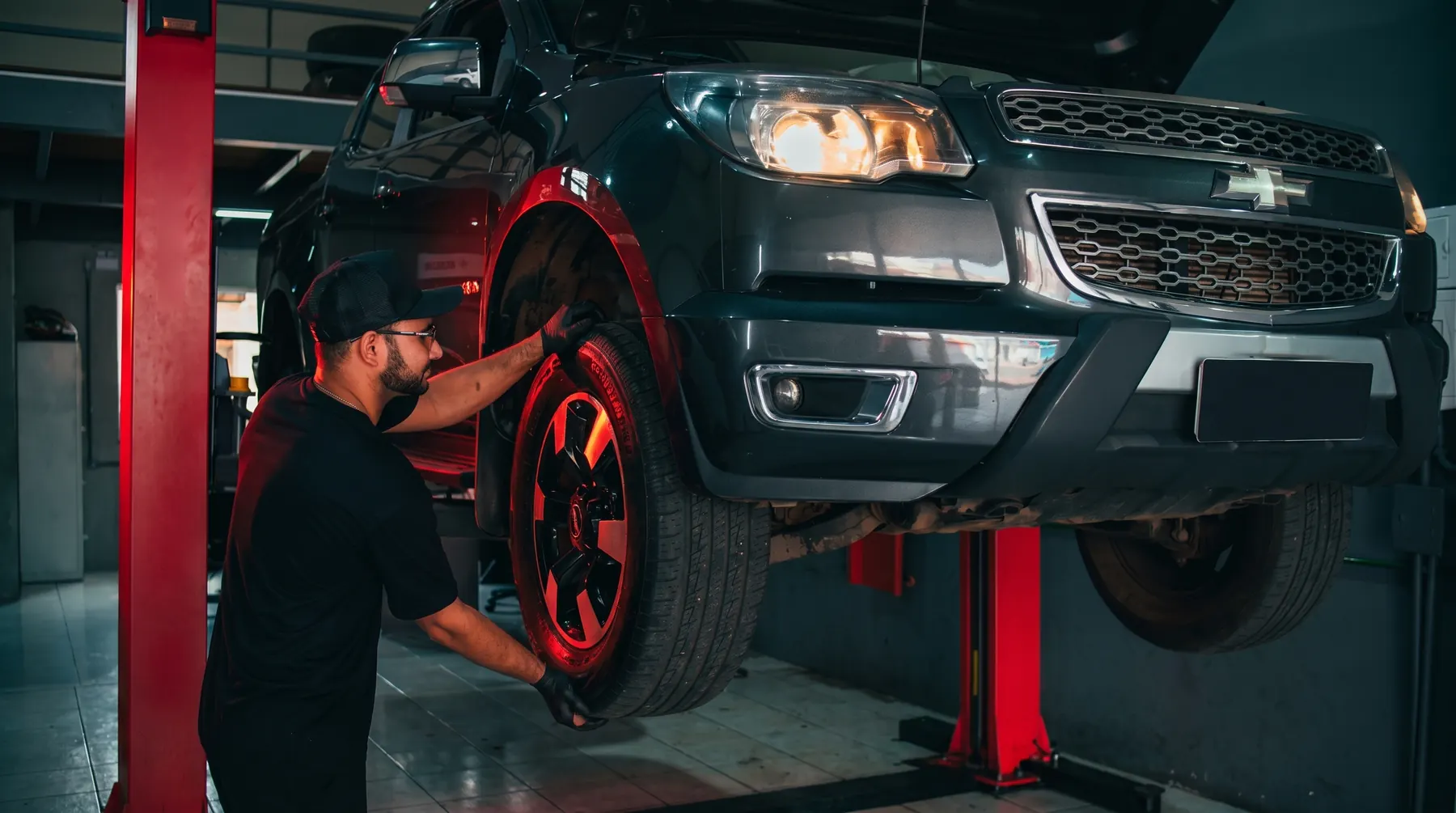 Mecânico da TS Auto Center trocando a roda de uma caminhonete no elevador da oficina